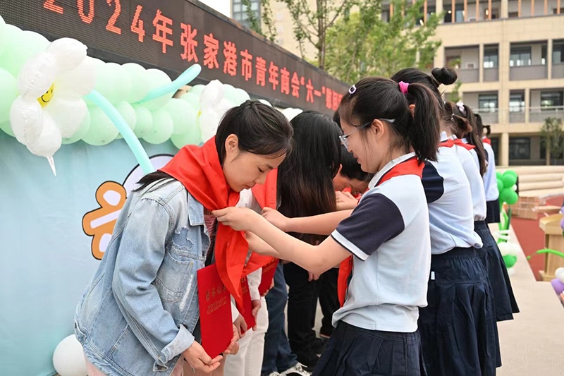 學生代表為愛心企業家代表敬獻（xiàn）紅領巾